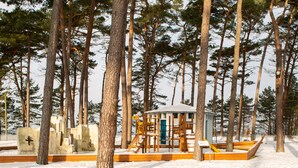 Zona cubierta de nieve con estructuras de juego de madera y un pequeño edificio.