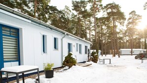 Un bâtiment blanc agrémenté de touches de bleu, un banc, un pot de fleurs et un sol recouvert de neige.