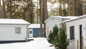 Una hilera de cabañas con nieve en el suelo, rodeadas de altos árboles.