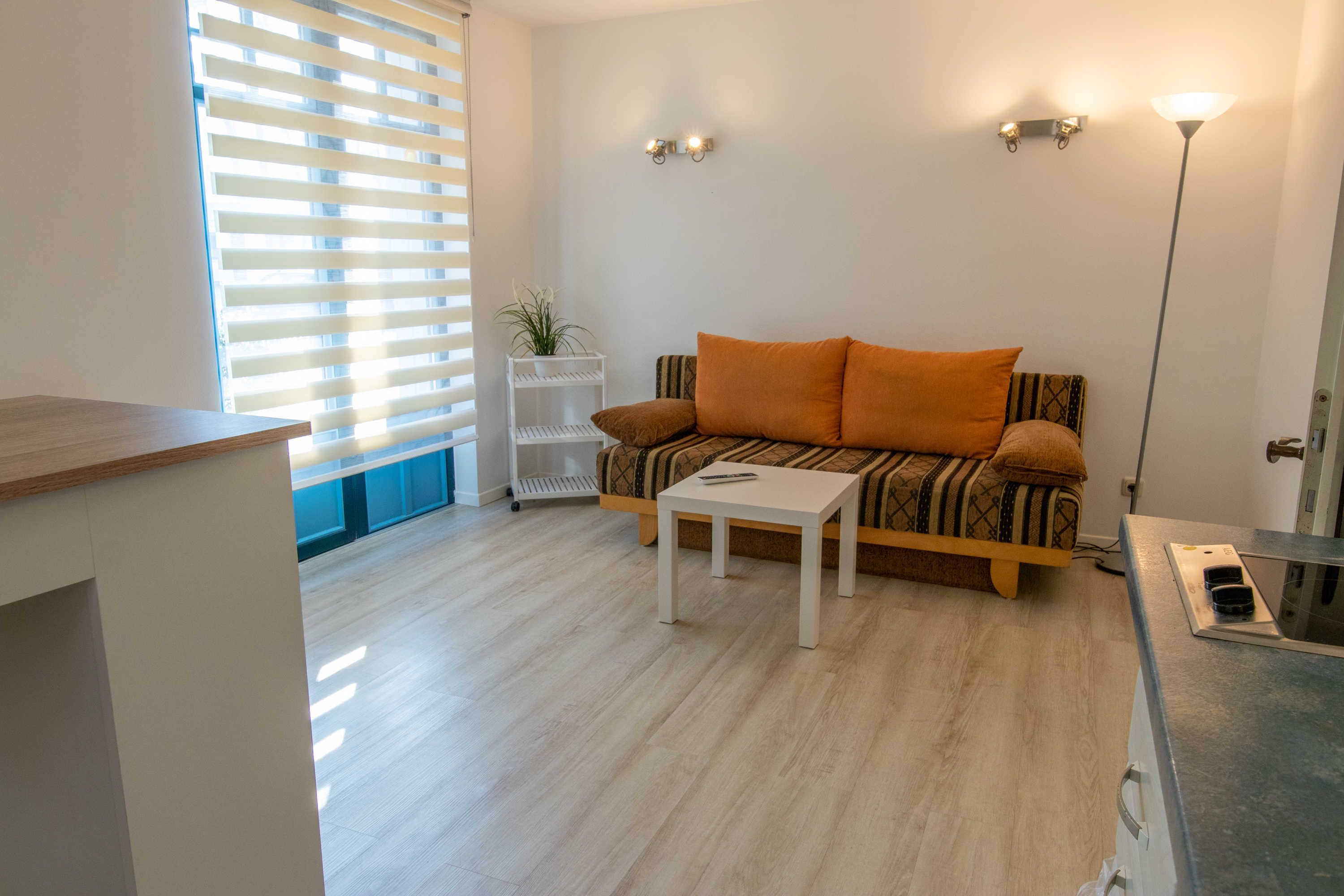 Un salon avec un canapé, une petite table, une étagère blanche et un lampadaire.