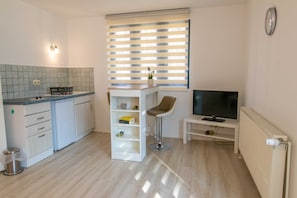 Een kleine keuken met een eethoek, een televisie en een radiator.