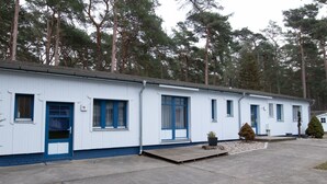 A row of white mobile homes with blue trim, numbered doors, and a small front porch area. - Vacation apartment 15 - Ferienanlage Zum Knirk (Lubmin (Seebad))