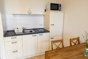 Una cocina con microondas, un lavabo y un florero con flores en la encimera.