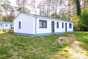 Um edifício térreo com telhado plano, porta frontal e pequena varanda.