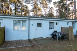 A white mobile home with a number '9' on the door, a small porch with two chairs, and a wooden fence.