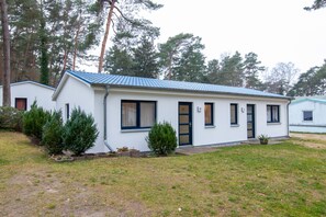 A single-story white building with a blue roof, a front door, and windows. - Vacation apartment 27 - Ferienanlage Zum Knirk (Lubmin (Seebad))