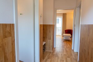 Ein Flur mit Holzboden, einem roten Sessel und einem kleinen Tisch.