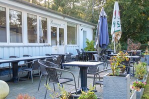 Ein Restaurant mit Außenbereich, einschließlich Tischen und Stühlen, und einem überdachten Bereich mit Sonnenschirmen.