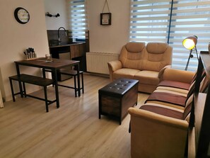 Een woonkamer met een bank, een salontafel, een eettafel en een keukenhoek.
