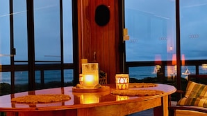 A wooden table with candles and a view of the sea through large windows. - Mid-century beach front house, on five private acres, dogs welcome (Dolphin Sands)