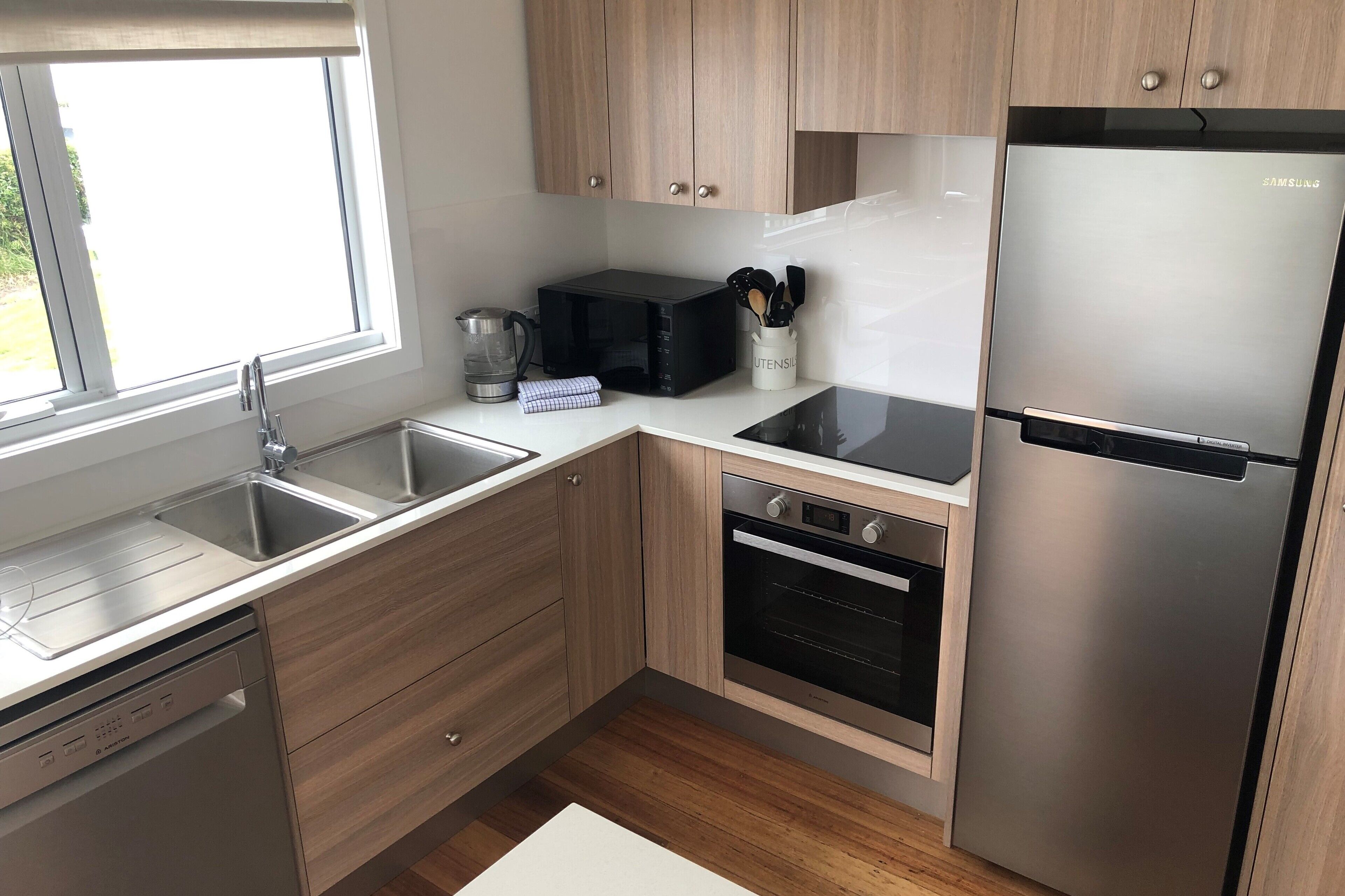 Una cocina moderna con electrodomésticos de acero inoxidable, armarios de madera y un ventanal que proporciona luz natural.