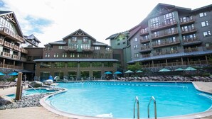 A hotel with a large pool, multiple balconies, and outdoor seating areas. - Lodge at Spruce Peak! Amazing 2 BR ! Ski In-Out! (Stowe)