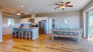 A spacious kitchen with a central island, wooden flooring, and a dining area with a rustic table and chairs.