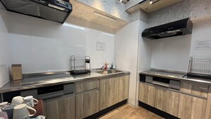 A modern kitchen with stainless steel appliances, wooden cabinets, and a black range hood. - Sutton Place Hotel Ueno (Tokyo)