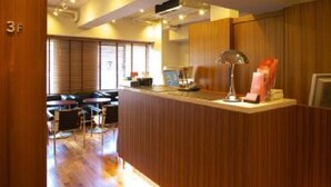 A modern kitchen with wooden cabinets, a countertop, and a dining area with chairs. - Sutton Place Hotel Ueno (Tokyo)