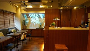 A modern kitchen with wooden cabinetry, a dining area with a wooden table and chairs, and a large window with a projection. - Sutton Place Hotel Ueno (Tokyo)