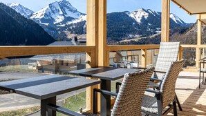 A wooden deck with tables and chairs, overlooking snow-capped mountains. - Apartment in French Alps with Wellness Centre (Abondance)