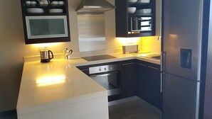 A modern kitchen with a central island, built-in oven, and a stainless steel refrigerator. - Apartment in Hotel Residence (Grand-Baie)