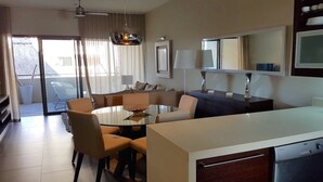 A modern hotel room with a dining area, a sofa, a coffee table, and a kitchen area. - Apartment in Hotel Residence (Grand-Baie)