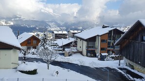 A snow-covered village with buildings, a road, and mountains in the background. - Studio for 2-4 Guests With Balcony and Panorama View (Emmetten)