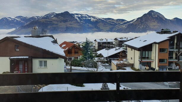 A residential area with snow-covered roofs and houses, a mountain range in the background, and a clear sky. - Studio for 2-4 Guests With Balcony and Panorama View (Emmetten)