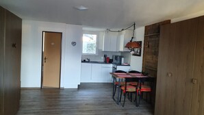A modern kitchen with white cabinets, a dining table with chairs, and a wooden floor. - Studio for 2-4 Guests With Balcony and Panorama View (Emmetten)