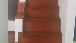 Un escalier en bois, muni d’une main courante, mène à une porte de couleur sombre.