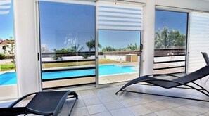 Une pièce dotée de grandes portes-fenêtres coulissantes, d’une piscine et de deux chaises longues.