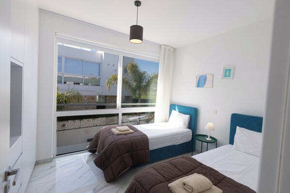 A modern hotel room with two beds, a large window, and a view of the outside. - Protaras Vie Bleu Villa Vb2 (Paralimni)
