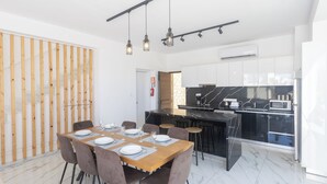 A modern kitchen with a black countertop, white cabinets, and a built-in microwave. - Protaras Vie Bleu Villa Vb2 (Paralimni)