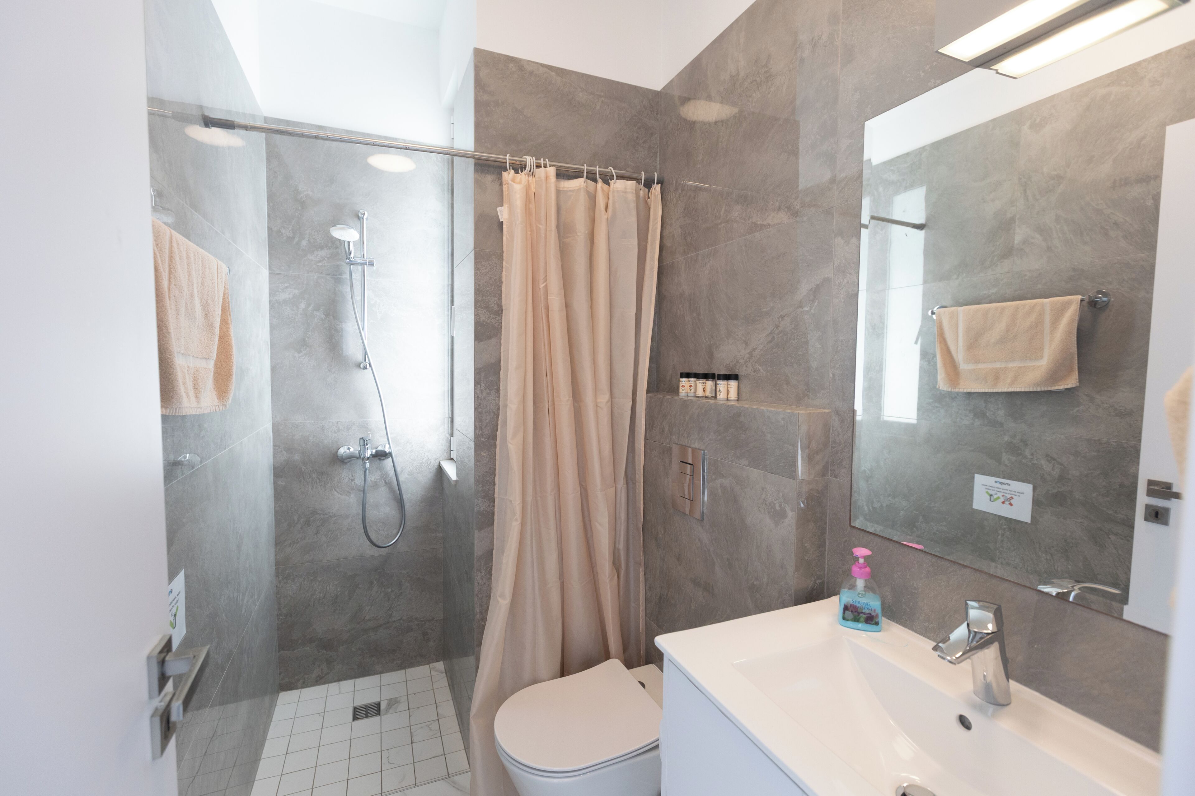 A modern bathroom with a glass shower enclosure, a toilet, a sink with a mirror, and a towel rack.