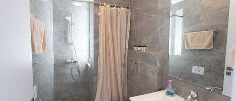 A modern bathroom with a glass shower enclosure, a toilet, a sink with a mirror, and a towel rack.