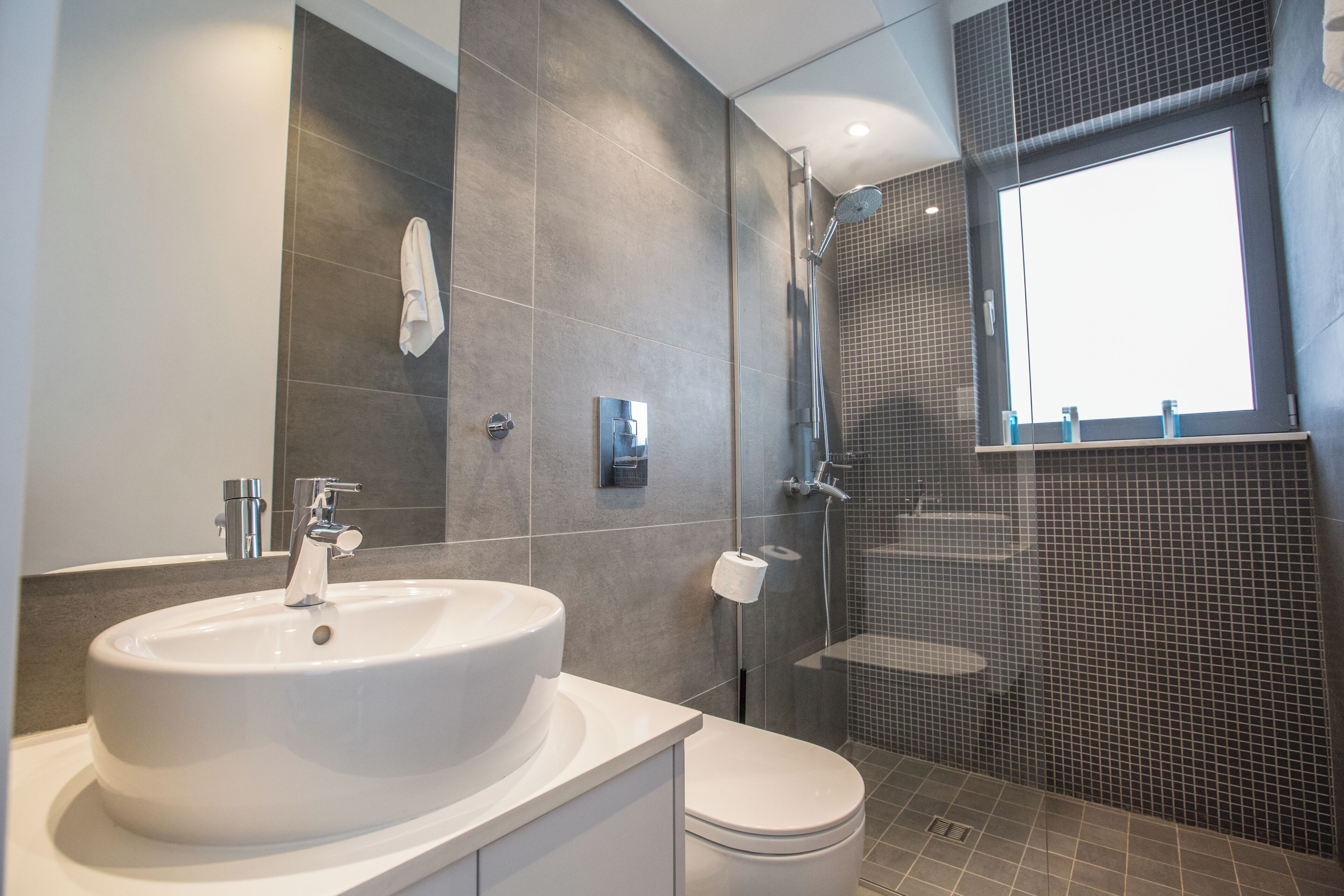A modern bathroom with a large sink, toilet, and shower area.