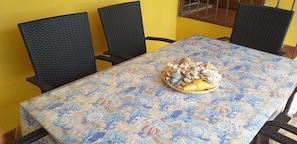 Una mesa de comedor con mantel floreado, rodeada de cuatro sillas negras.