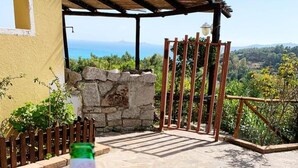 A bottle of Ichnuso Limon on a stone patio with a view of the sea and mountains.