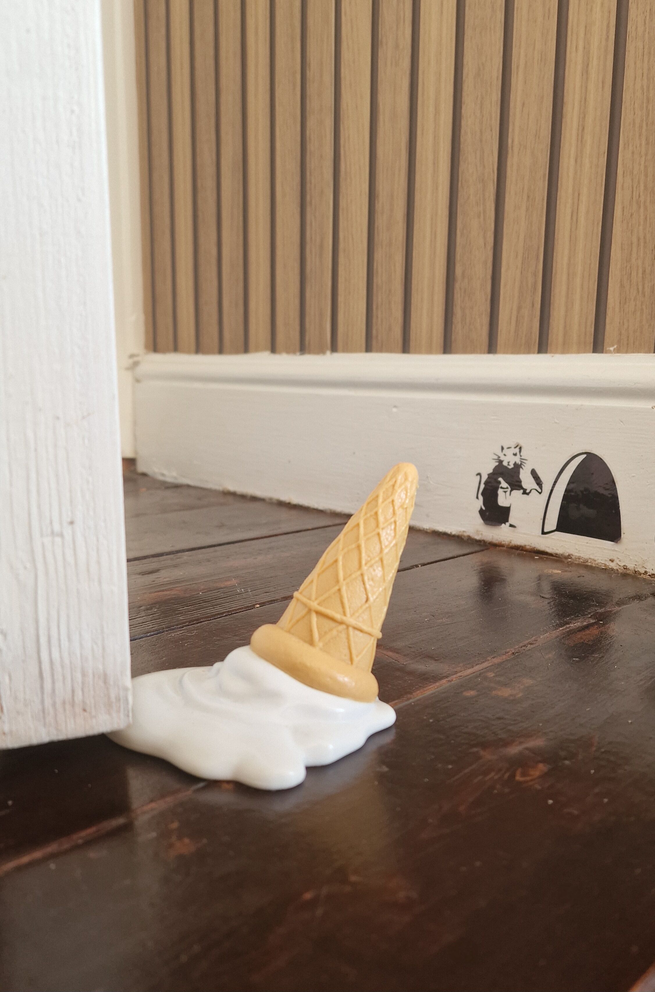 Un plancher en bois avec une plinthe blanche et une fresque murale représentant un chat noir.