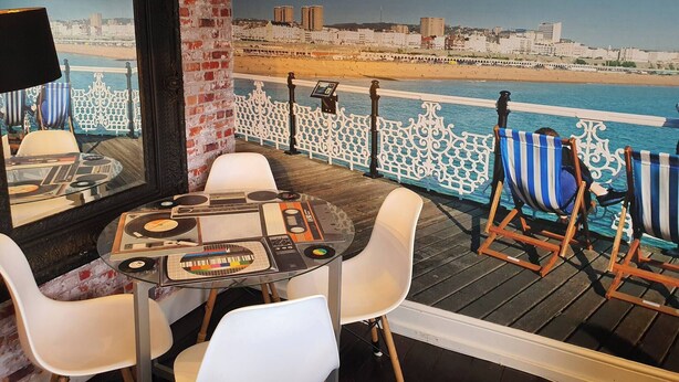 A deck with a DJ setup, white chairs, and a view of the beach and cityscape. - 3 Bed House Stunning Views And Free Parking (Brighton)