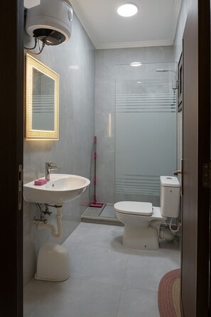 Un baño moderno con lavamanos, inodoro y ducha blancos.