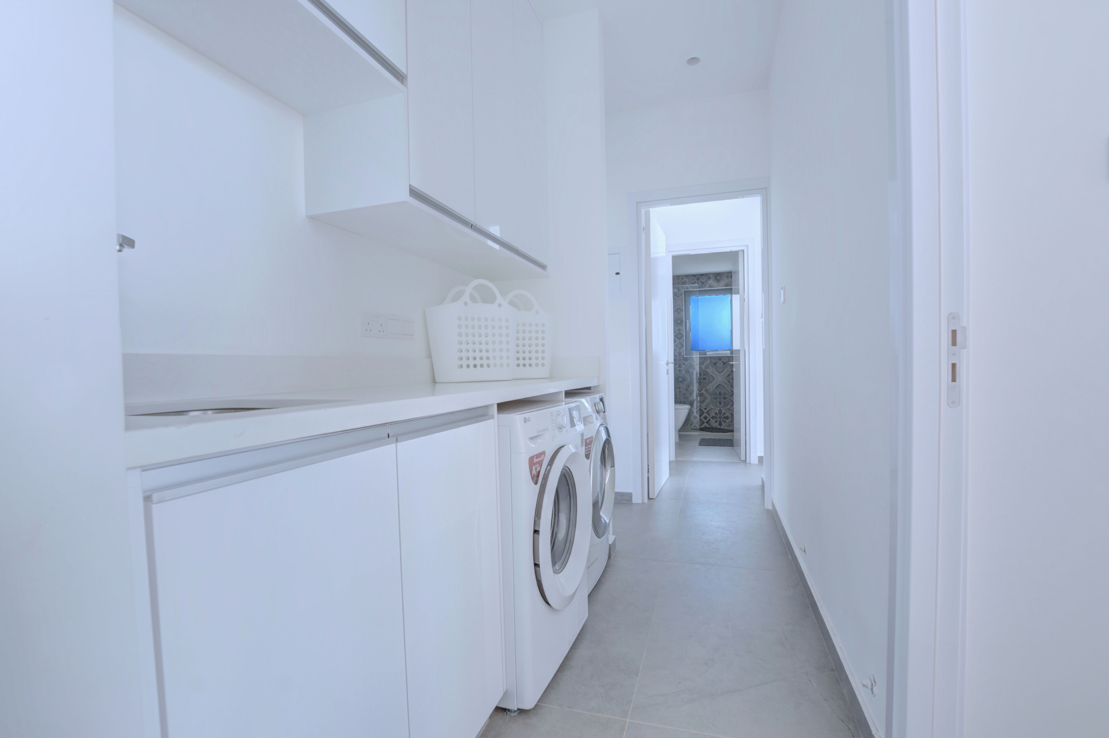 A laundry area with a washing machine and dryer, a white countertop, and a basket.