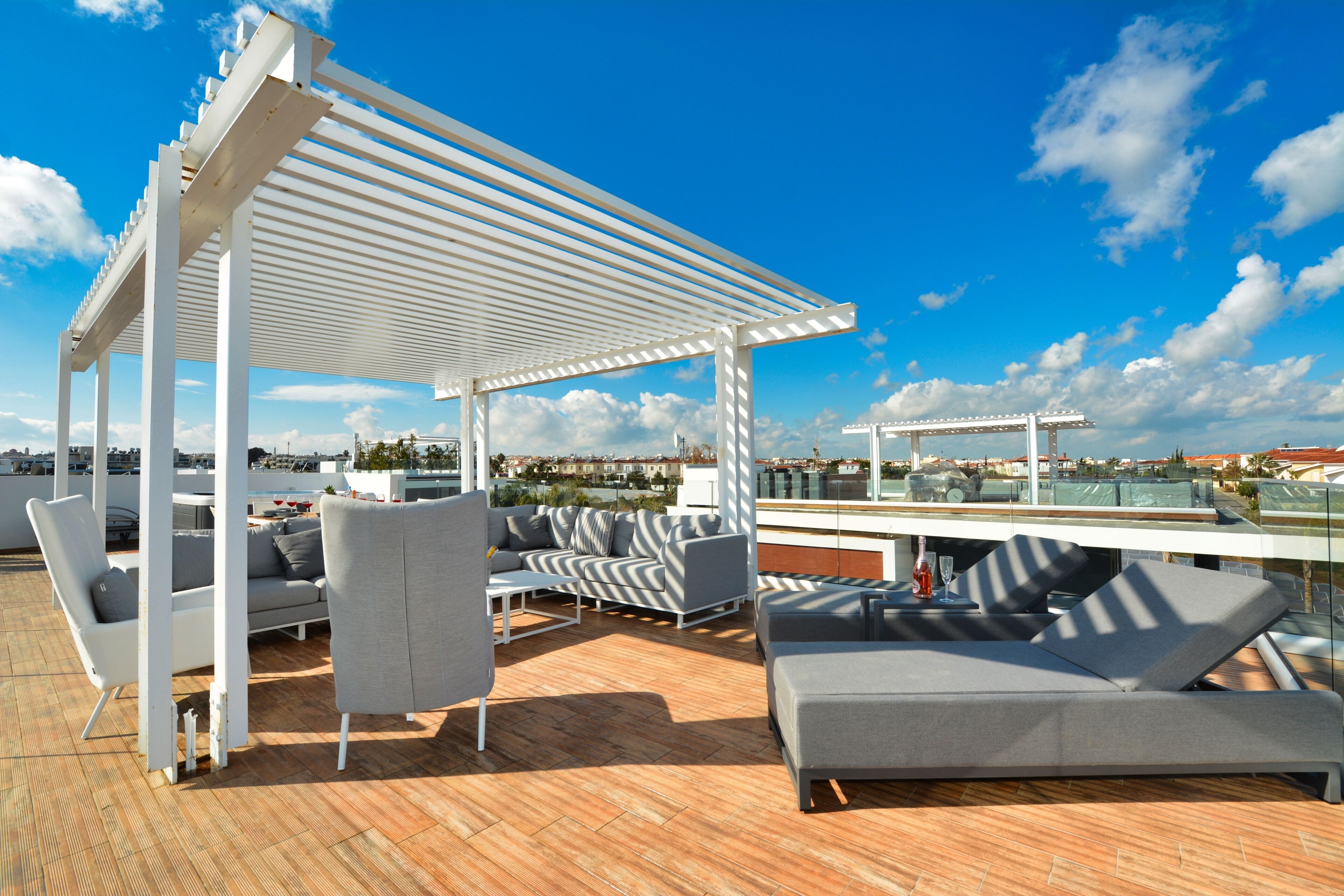 A rooftop terrace with a pergola, outdoor seating, and a view of the cityscape.
