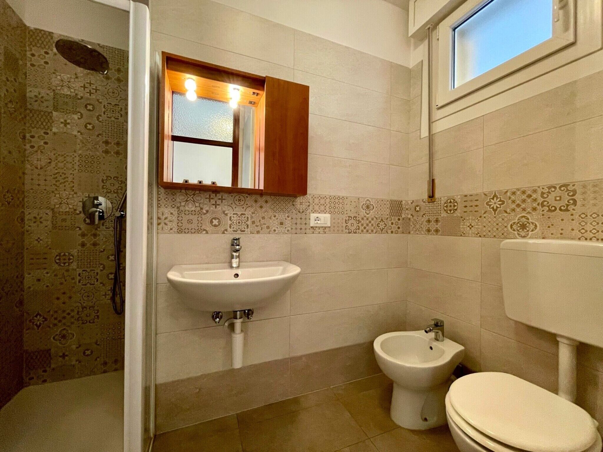 A bathroom with a sink, bidet, toilet, and a shower area.