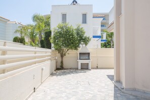 Enjoy al fresco dining in this charming courtyard with a barbecue grill and a tree in the center.