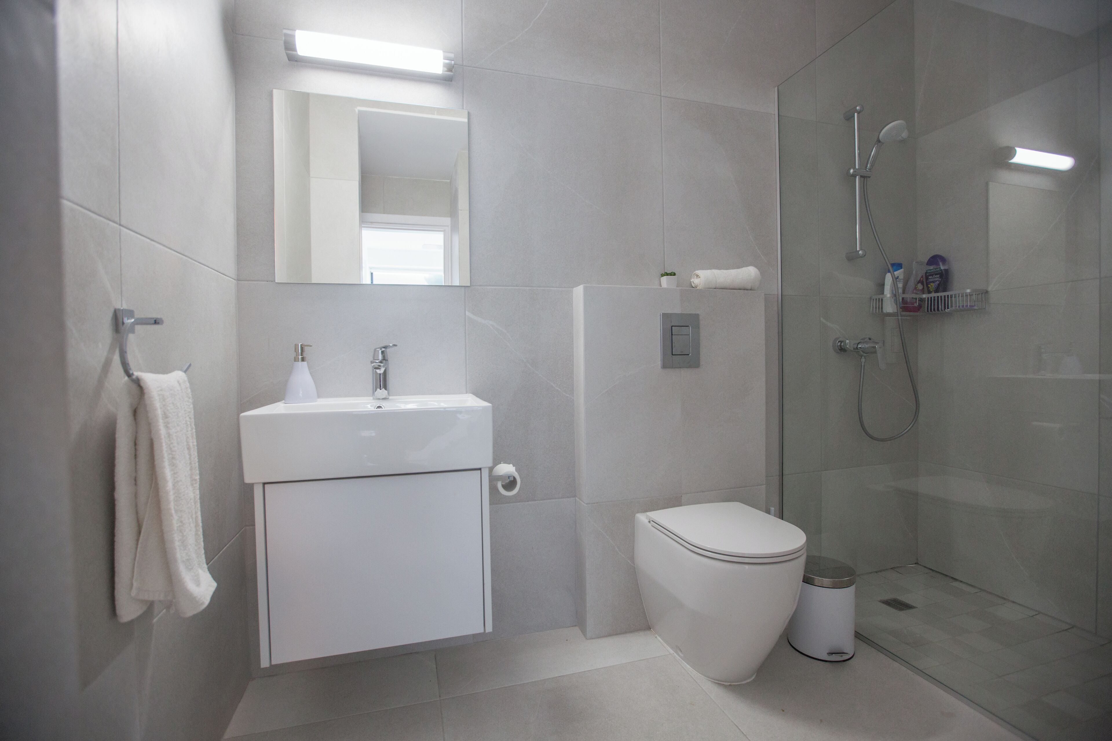 Un baño moderno con inodoro, lavamanos y ducha.