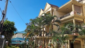 Un immeuble résidentiel à plusieurs étages, doté de balcons, d’une piscine et d’une végétation luxuriante.