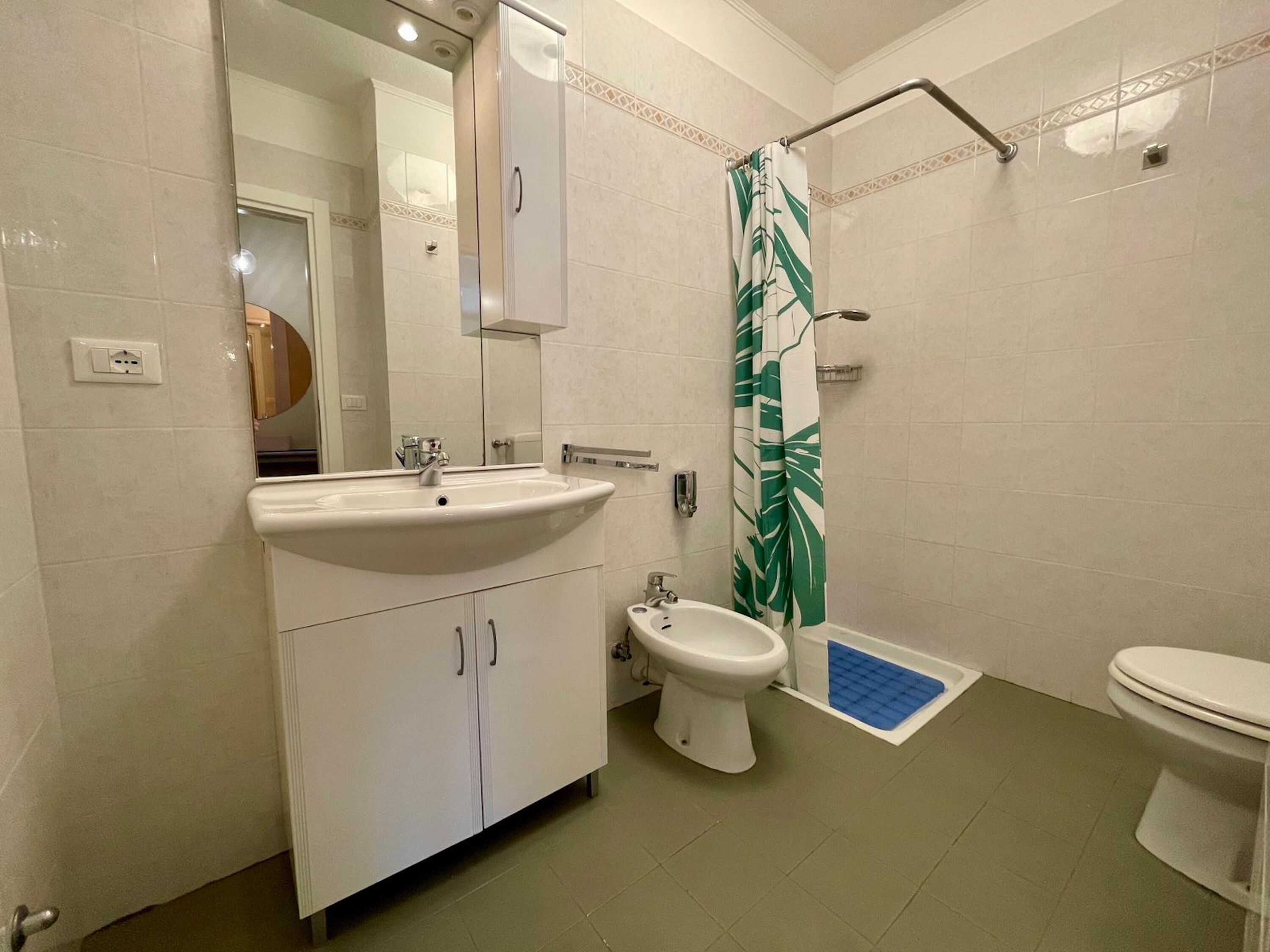 A bathroom with a sink, mirror, toilet, and shower curtain.