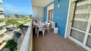 Ein Balkon mit Tisch für zwei Personen, einem Blumentopf und einer weißen Klimaanlage.