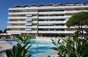 Um hotel com vários andares, varandas, piscina e vegetação exuberante.