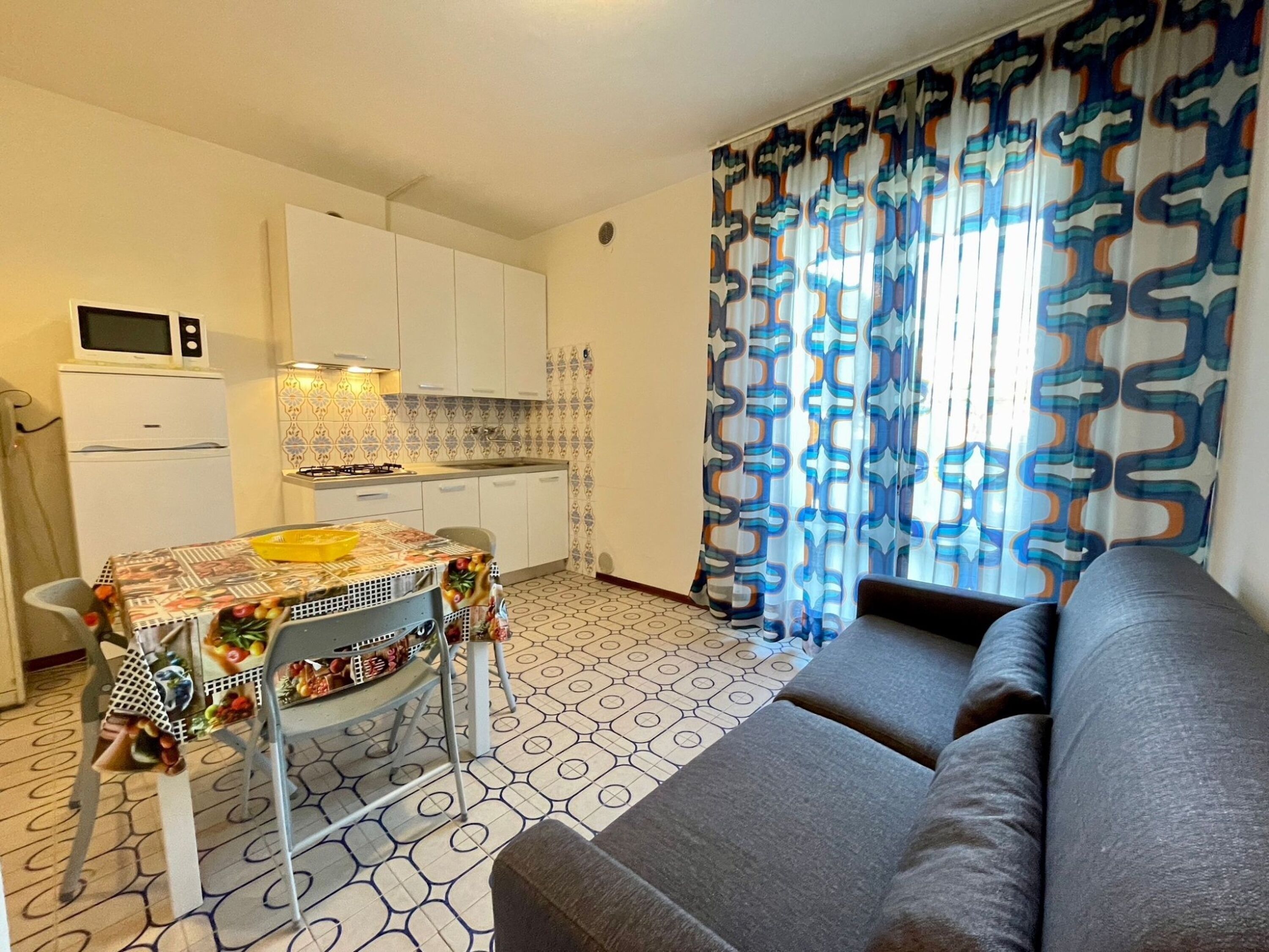 A compact living space with a kitchenette, a dining table with chairs, and a sofa.