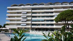 Ein mehrstöckiges Hotel mit Balkonen, einem Schwimmbad und üppiger Bepflanzung.