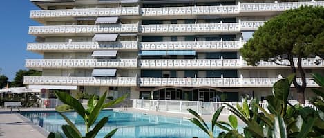 Un hôtel à plusieurs étages doté de balcons, d’une piscine et d’une végétation luxuriante.